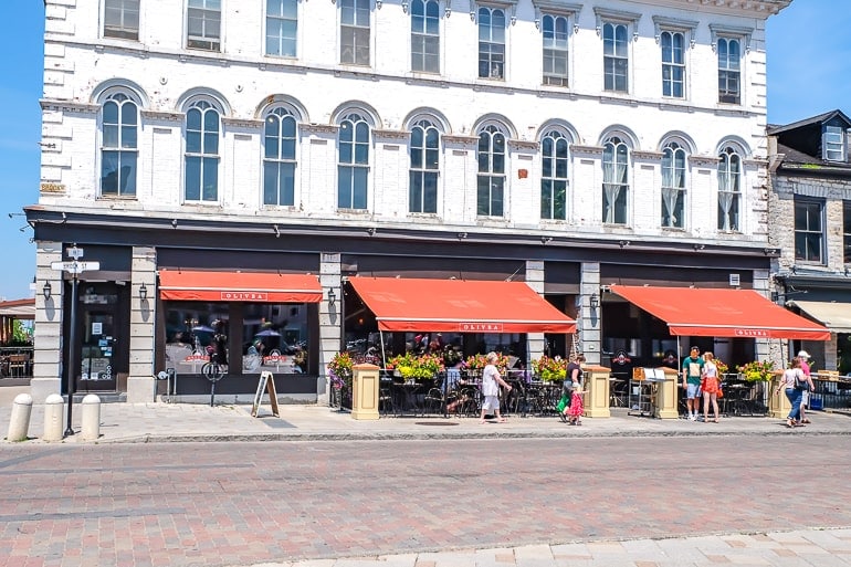 italian restaurant in white building with orange patio covers and sidewalk in front