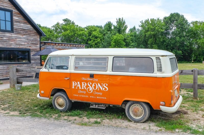 orange vintage van parked by wooden fence at parsons brewery in prince edward county