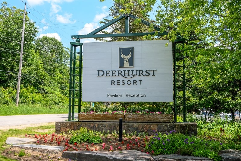 large wooden sign outside deerhurst resort with trees behind