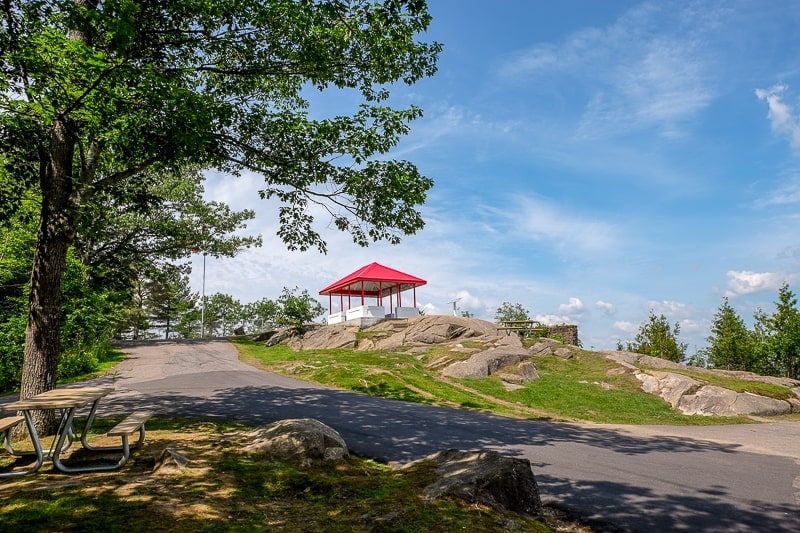 red pavilion at top of lookout point with trees and rock around