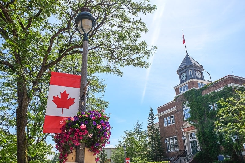 canadian flag on street lamp with old town hall behind
