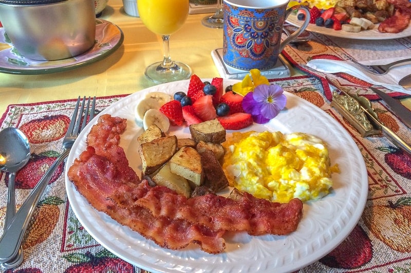 eggs and bacon on breakfast plate on table with mug
