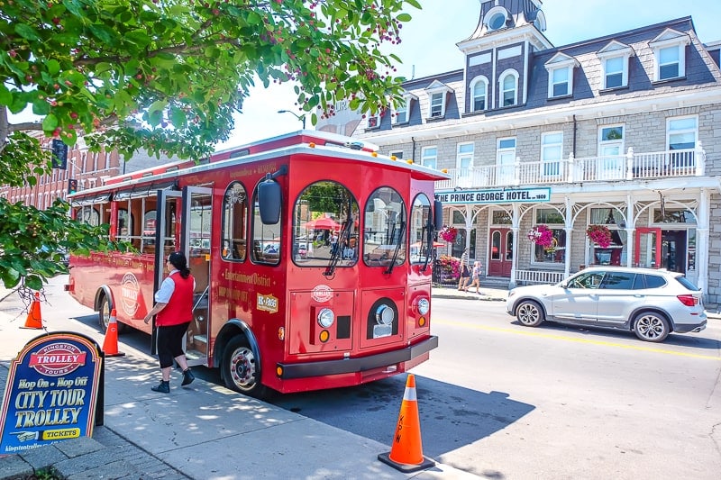 red old trolley car parked on street with old building behind in kingston ontario