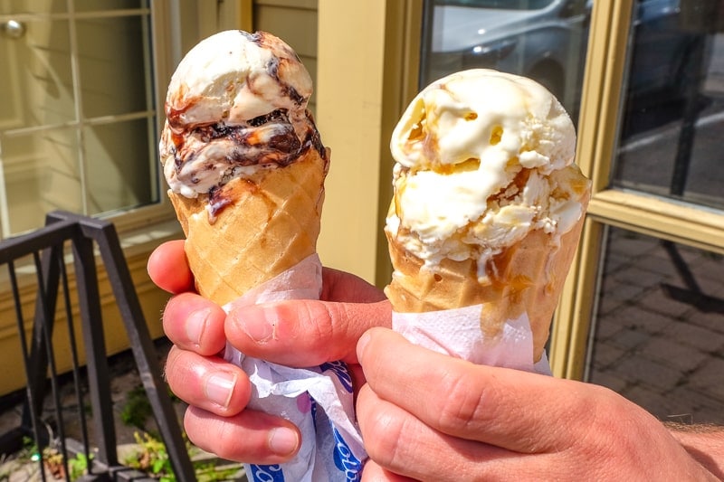 two ice cream cones from cows ice cream held in hand outside shop