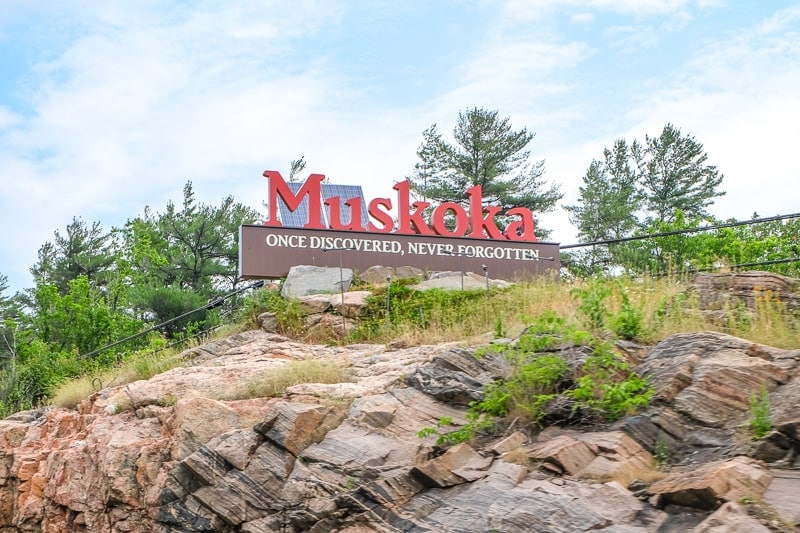 red muskoka sign on rock cliff high above highway