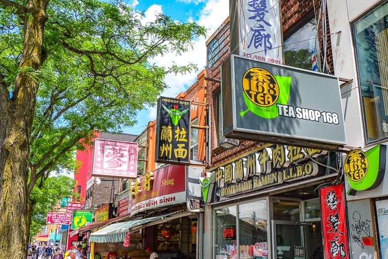 colourful signs with asian writing and green trees in toronto chinatown.