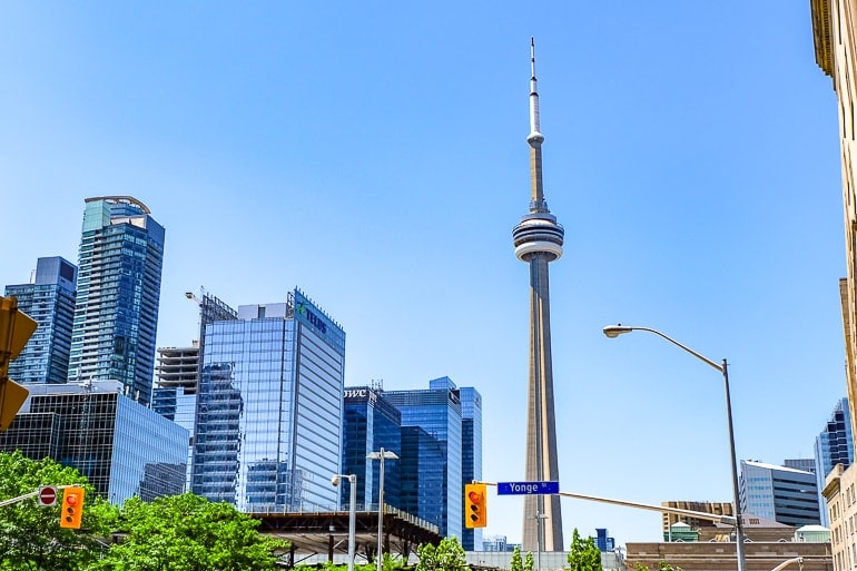 tall concrete cn tower among metal and glass skyscrapers with blue sky behind