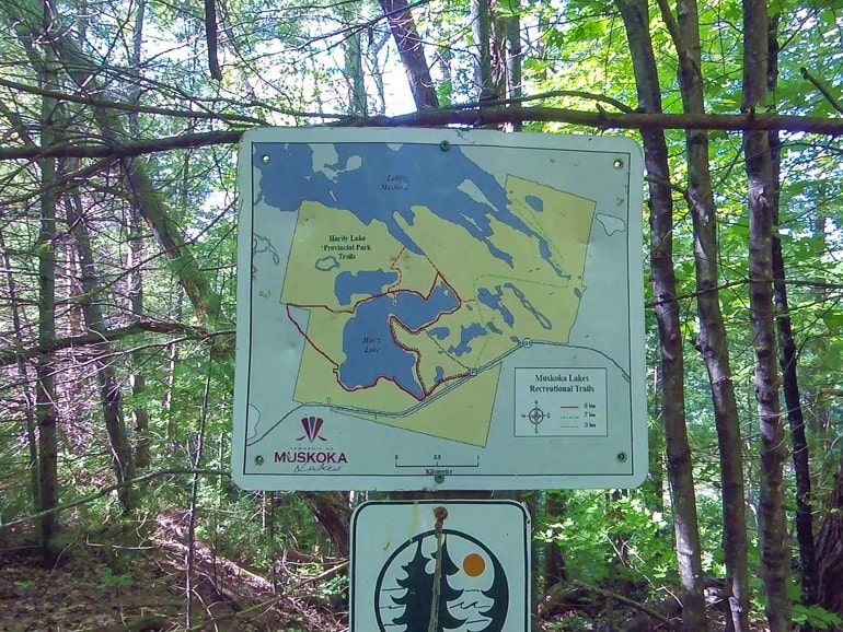 sign with trail map and forest trees behind