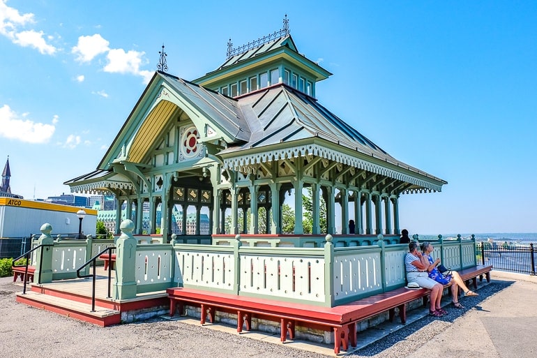 colourful pavilion with women sitting in front and blue sky behind.