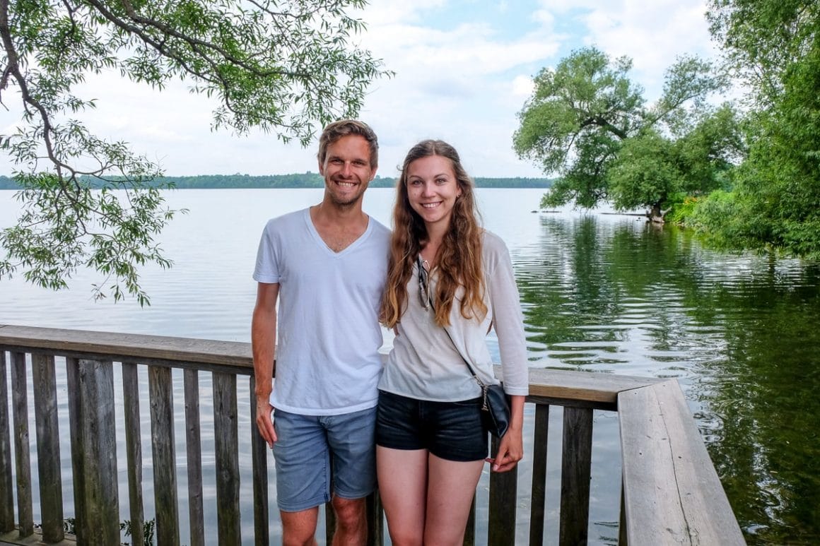 guy and girl wearing white standing in front of lake