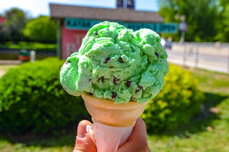 mint chocolate chip ice cream cone in front of sign