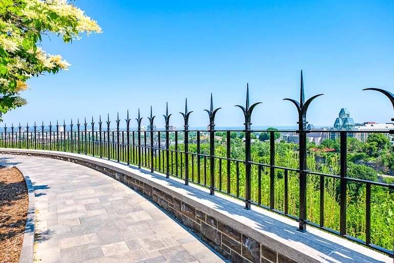 iron fence with stone pathway in front and views behind of ottawa river