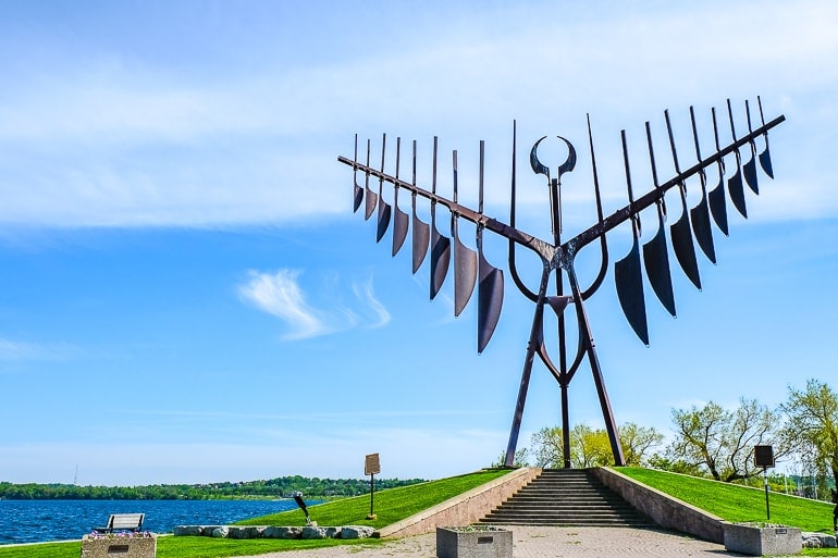tall metal sculpture with wings at barrie waterfront with blue sky behind