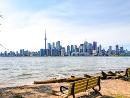 tall buildings of toronto skyline with beach and benches in foreground