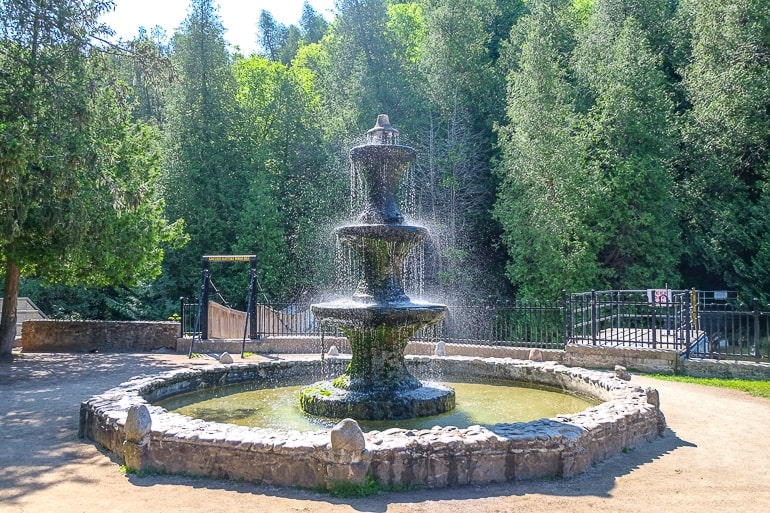 fountain spraying water with green trees behind.