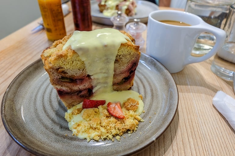 french toast with sauce on plate with coffees on wooden table .