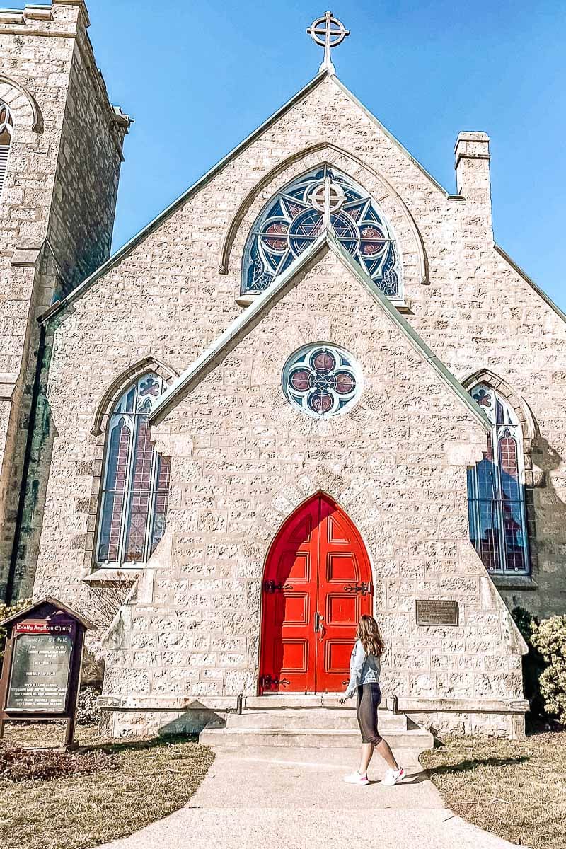 woman exploring stone church with red door