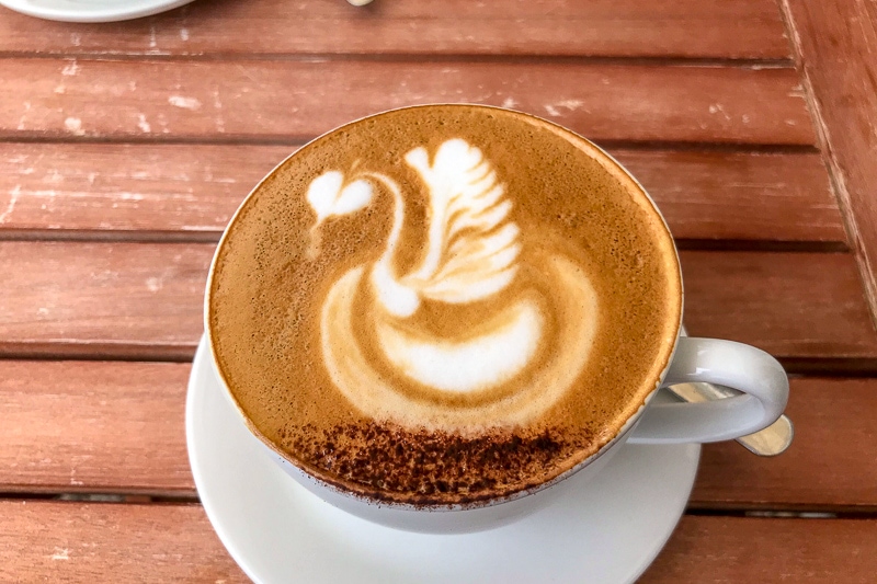 latte art of swan in white mug on wooden table