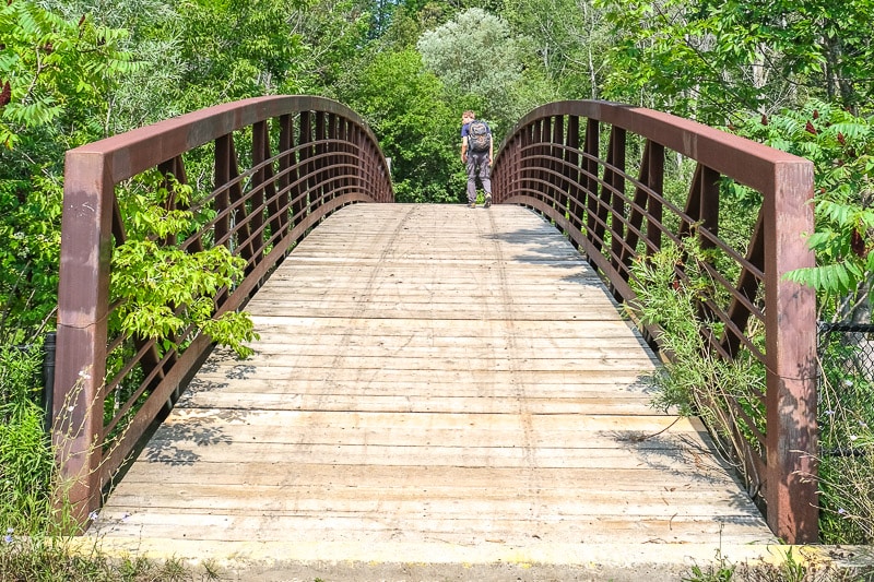 large wooden bridge with metal sides and man waling across.