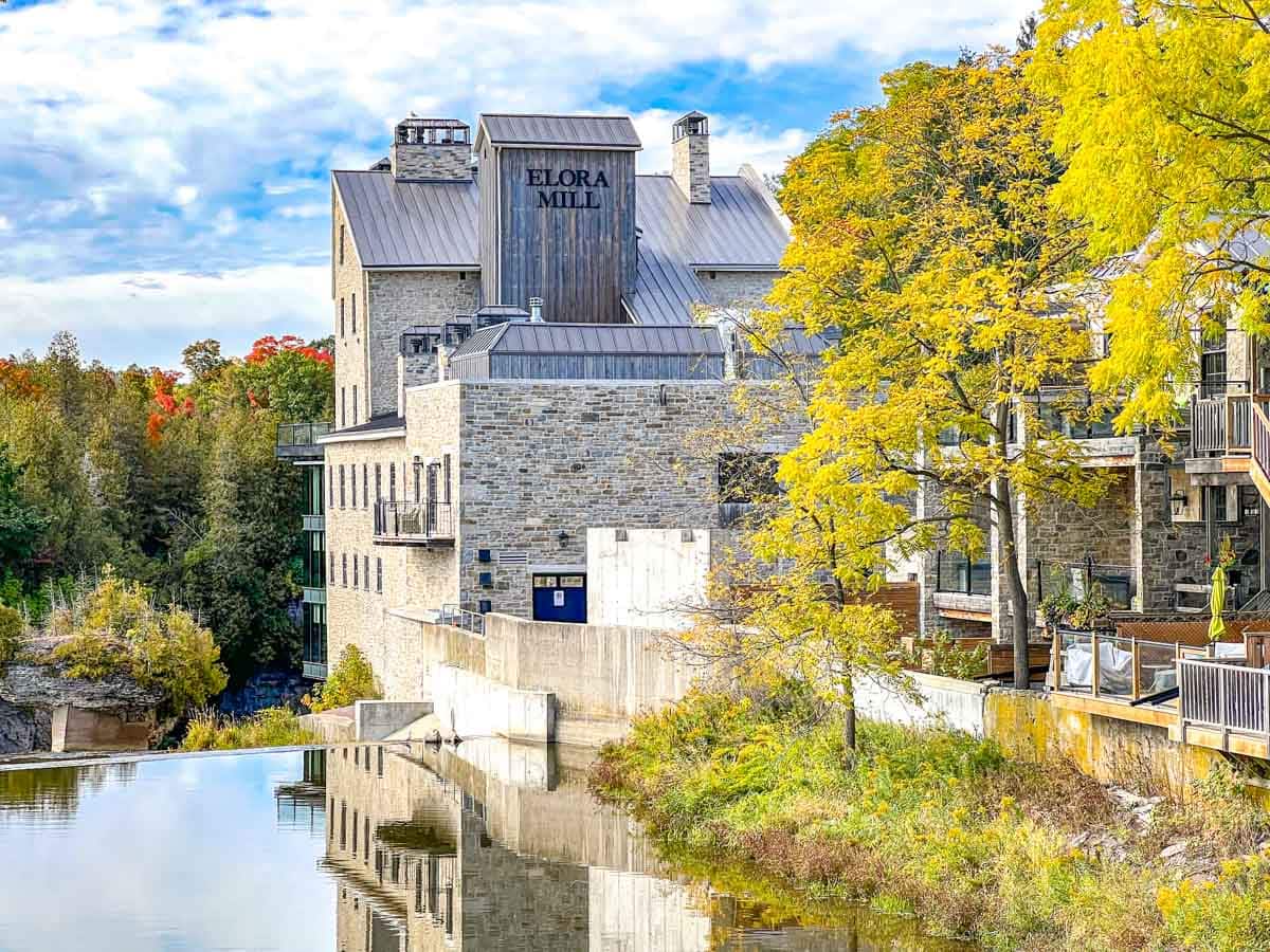 view of historic inn hotel reflective off the river in front in elora ontario.
