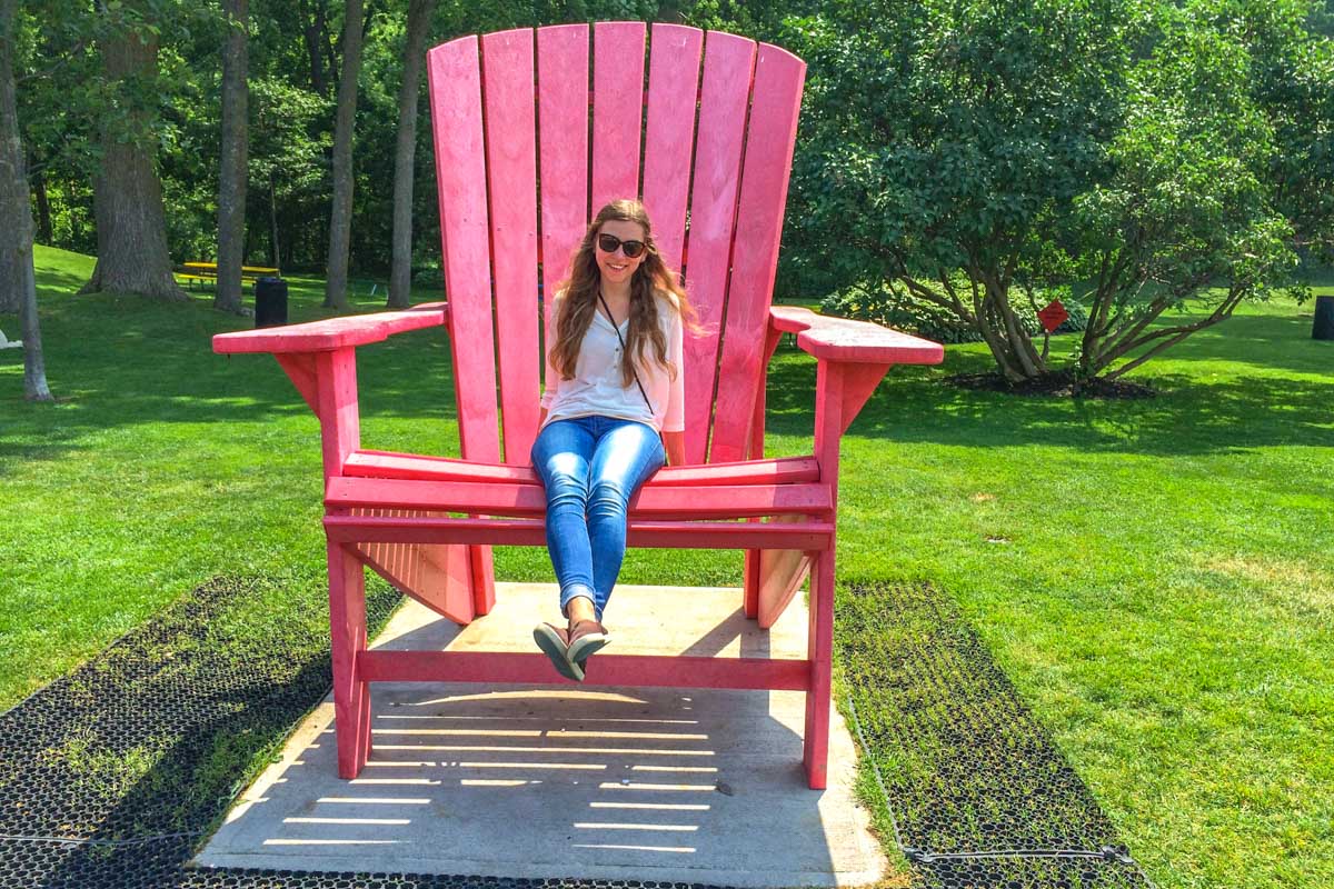 woman with sunglasses sitting in large red chair outdoors.