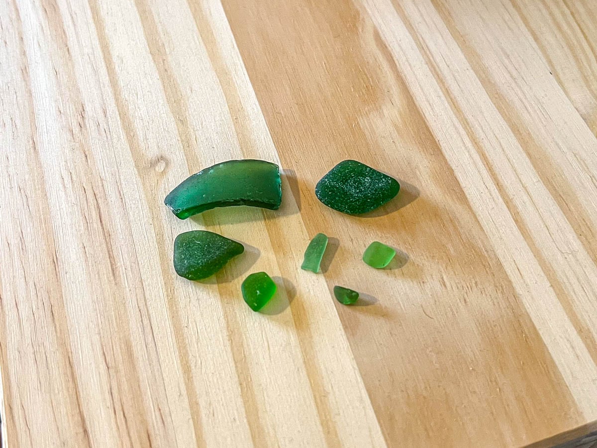 green pieces of beach glass on wooden table.