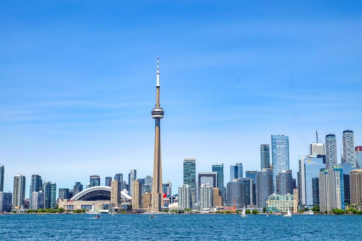 toronto city skyline seen from water with cn tower in middle and blue sky above.