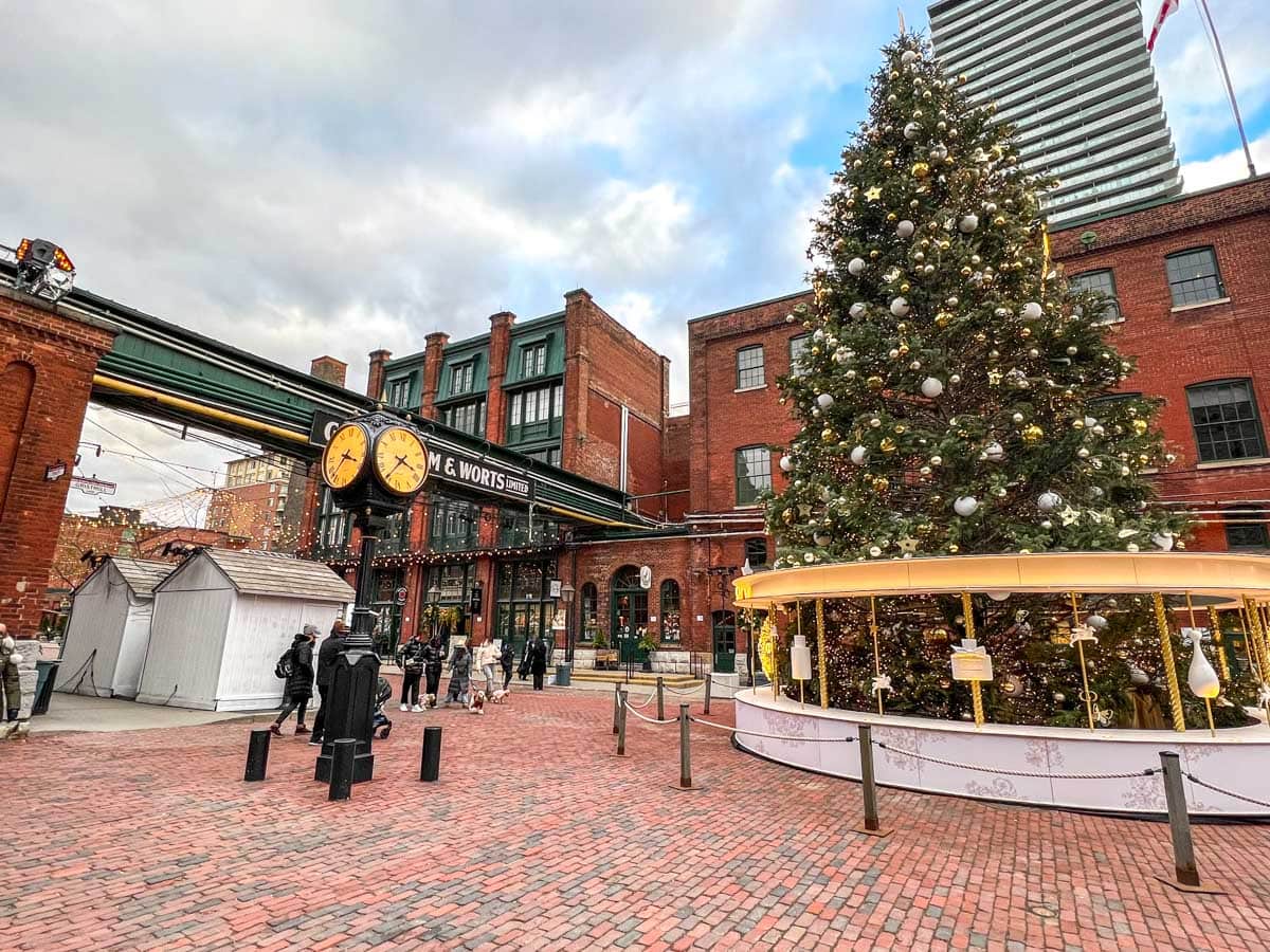 red brick district with christmas tree clock tower and people walking around.